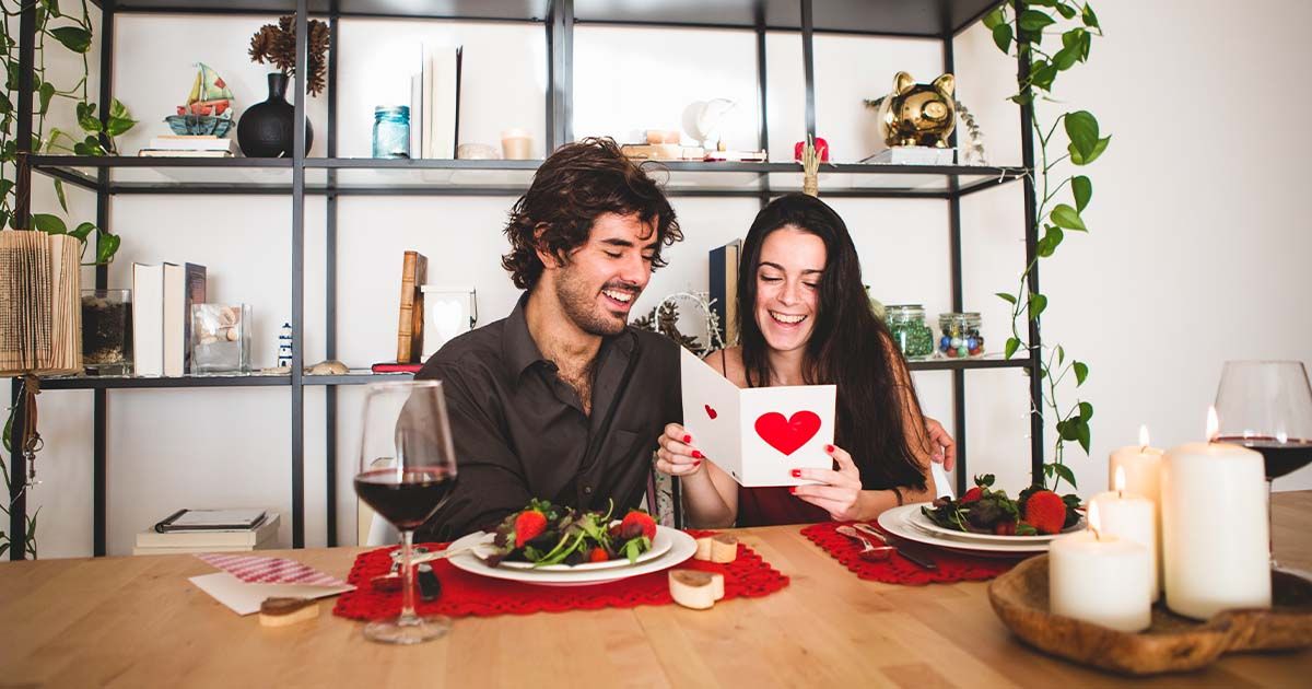 Couple reading Valentine's day card while at romantic dinner.